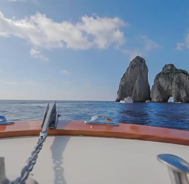 View from private boat tour approaching the Faraglioni rock arch in Capri Italy