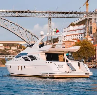 White luxury yacht sailing under Ponte Luís I bridge on the Douro River in Porto