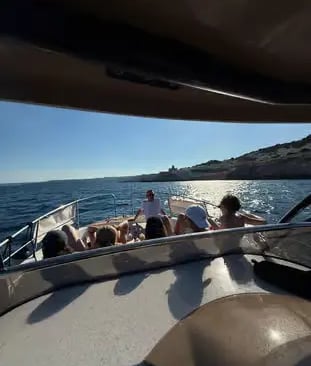 Group relaxing on private charter boat deck cruising Adriatic coast near Castro Puglia