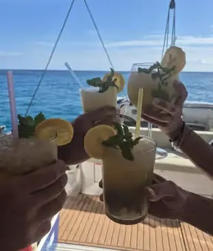 Friends toasting fresh cocktails on a catamaran with open Balearic Sea behind