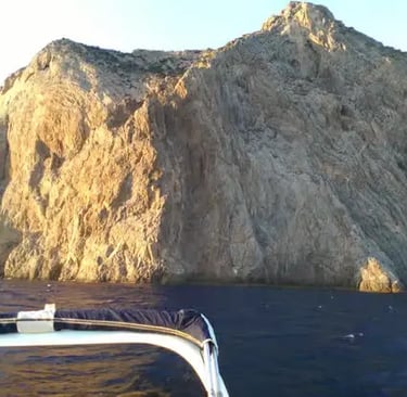 Dramatic limestone cliffs of Capo Teulada seen from a dinghy on the sea