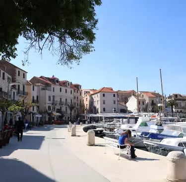 Sunny stone promenade in Vis Town with docked boats and Mediterranean houses