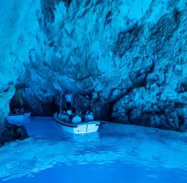 Glowing blue interior of Biševo Blue Cave with small tour boat inside, Croatia