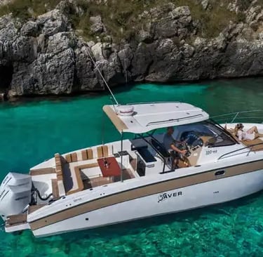 Modern private boat anchored in crystal turquoise water beside limestone cliffs in Salento