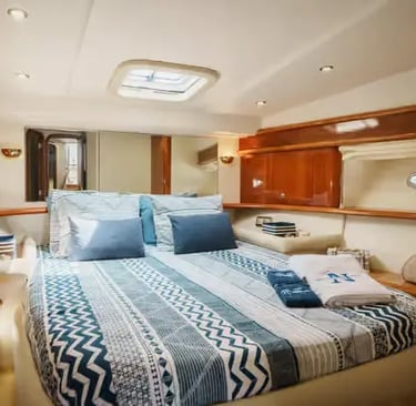 Cozy master cabin on a Douro yacht with double bed, nautical bedding and round porthole.