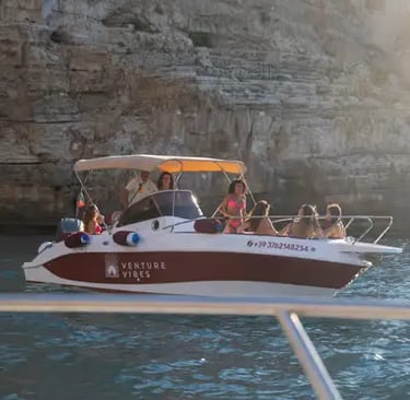 Group enjoying Monopoli boat tour with shaded canopy near limestone cliffs at sunset