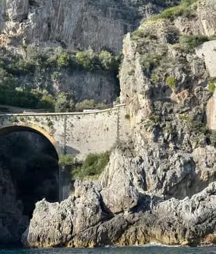 Fiordo di Furore stone bridge and vertical limestone cliffs seen from water level