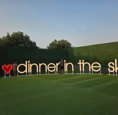 Guests posing at illuminated I Love Dinner in the Sky sign on Dubrovnik launch site lawn