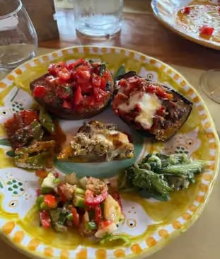 Colorful appetizer plate with bruschetta and fresh vegetables on hand-painted Italian ceramic