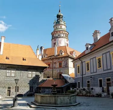 Iconic round tower of Český Krumlov Castle with fountain in sunny courtyard