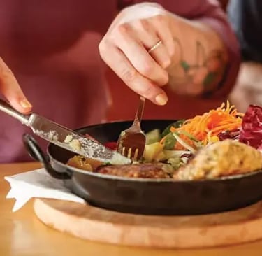 A close-up of a traveler enjoying a traditional Austrian mountain dish in a pan,