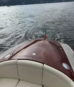  Polished wooden boat deck with Italian flag cruising on Lake Como private tour