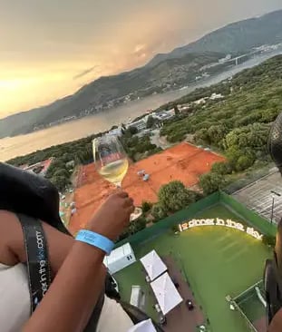 Guest holding white wine with aerial Adriatic coastline sunset view at Dinner in the Sky Dubrovnik