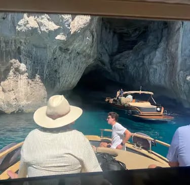Small boat entering Blue Grotto cave in Capri with turquoise water and limestone cliffs