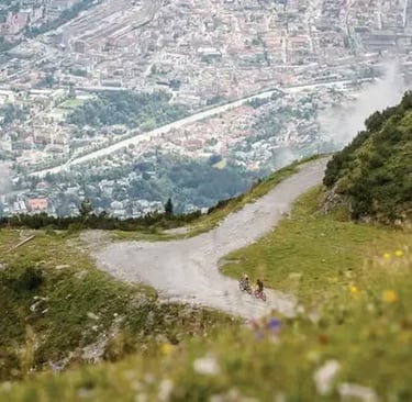 High angle view of a wide hiking and biking trail on Nordkette mountain overlooking the city of Innsbruck and the Inn River 