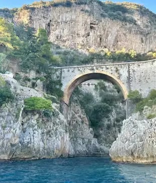 Historic stone arch bridge between dramatic limestone cliffs on the Amalfi Coast