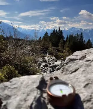 Compass on rock with panoramic Dachstein mountain views on Alpine hiking trail