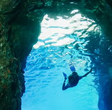 Snorkeler swimming through an underwater cave in crystal-clear Amalfi Coast waters