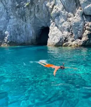 Snorkeler floating in crystal turquoise water near a Capri sea grotto during private boat tour