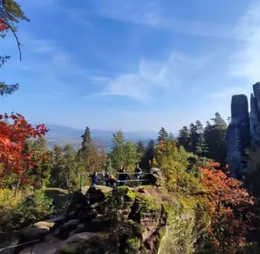 Hikers at a sandstone viewpoint in Bohemian Paradise with fall foliage and rock towers