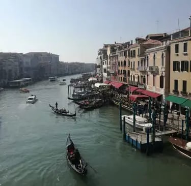 Wide view of the Grand Canal in Venice with gondolas, water buses, and historic buildings.