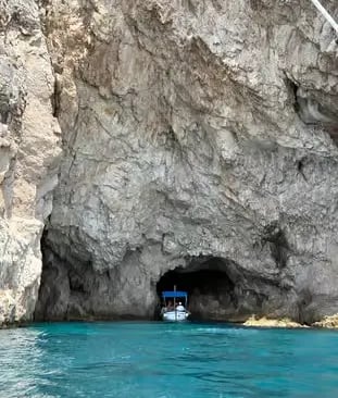 Narrow Blue Grotto cave entrance in Capri with small wooden boat waiting on turquoise water