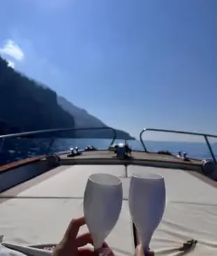 Two Prosecco glasses raised in a toast on a boat cruising the Positano coastline