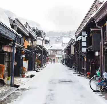 Snowy street lined with traditional Japanese wooden buildings.