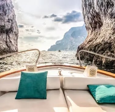 Private tour boat passing between limestone cliffs on Amalfi Coast snorkeling stop