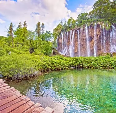 Wooden boardwalk along turquoise lake and waterfall at Plitvice, Croatia