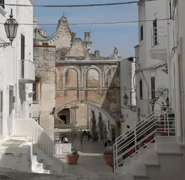 Whitewashed alley with baroque church and stone staircase in Ostuni, the White City of Puglia