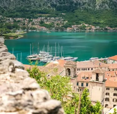  Elevated view of Kotor old town and turquoise Bay of Kotor with yachts and green mountains