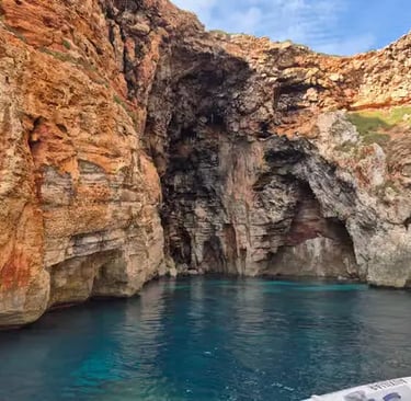 Turquoise water inside red limestone sea cave on Menorca southern coastline