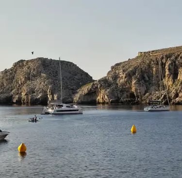 Catamarans and boats anchored in sheltered rocky bay along Menorca coast
