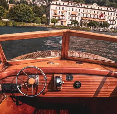 Vintage wooden boat cockpit steering toward historic villa on Lake Como