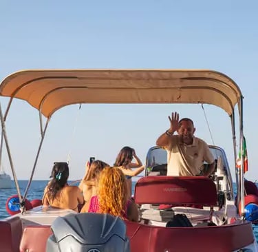 Smiling Italian boat captain waving with passengers on flexible Puglia coast tour at golden hour