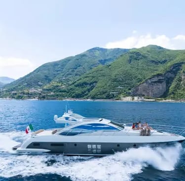 Azimut luxury yacht cruising at speed along green Italian coastline with Italian flag