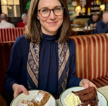 Woman holding plates of Apple Strudel and Sachertorte in a Vienna cafe.