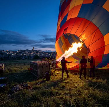 Crew inflating a hot air balloon with burner flame at dawn near Matera, Italy