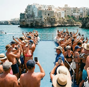 Packed group tour boat with dozens of tourists raising phones in front of Polignano cliffs