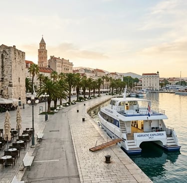 Tour boat docked at Split Riva promenade with Diocletian's Palace bell tower at sunrise