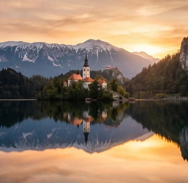 Lake Bled Slovenia at sunrise with island church, castle cliff and Alpine peaks reflected