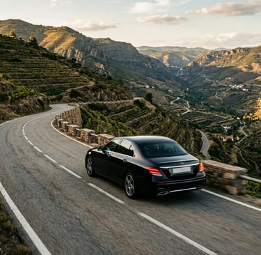 Private luxury sedan on a winding mountain road through Priorat vineyards