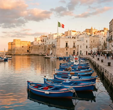  Traditional blue fishing boats moored in Monopoli old port with castle and white town at golden hour