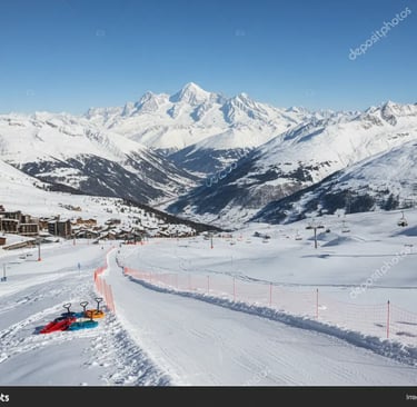 A wide scenic view of a snow-covered mountain valley and ski slopes under a clear blue sky.