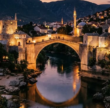 The historic Stari Most stone bridge glowing at night reflected in the Neretva River in Mostar, Bosnia