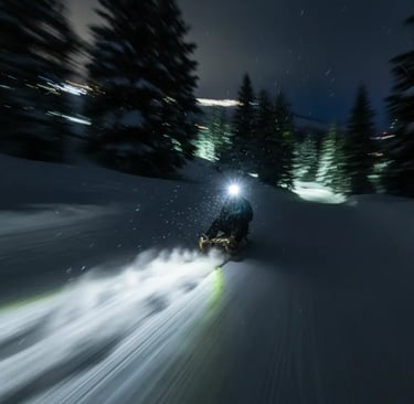 A person riding a sled down a snowy mountain at night with a bright headlight creating a motion blur