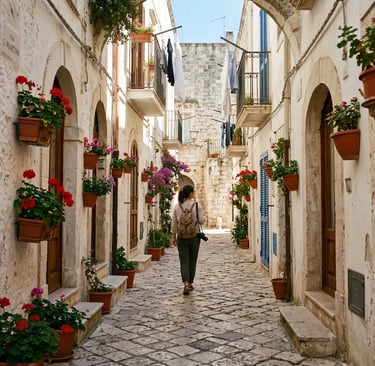 Traveler walking cobblestone alley in Monopoli old town with flower pots Puglia Italy