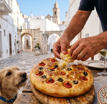 Hands tearing fresh focaccia barese in Ostuni white city alley with curious dog watching