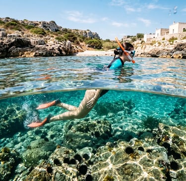 Woman snorkeling in crystal-clear water above rocky seabed, Puglia coastline